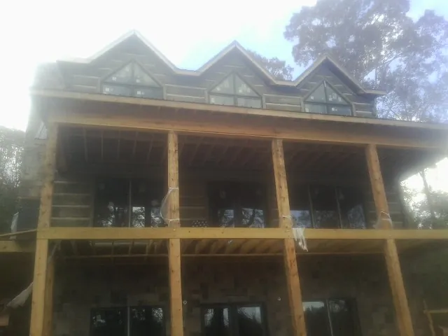 Dormers and porch framing on a large log home under construction — Roof Coating work by our crew in Mcmechen