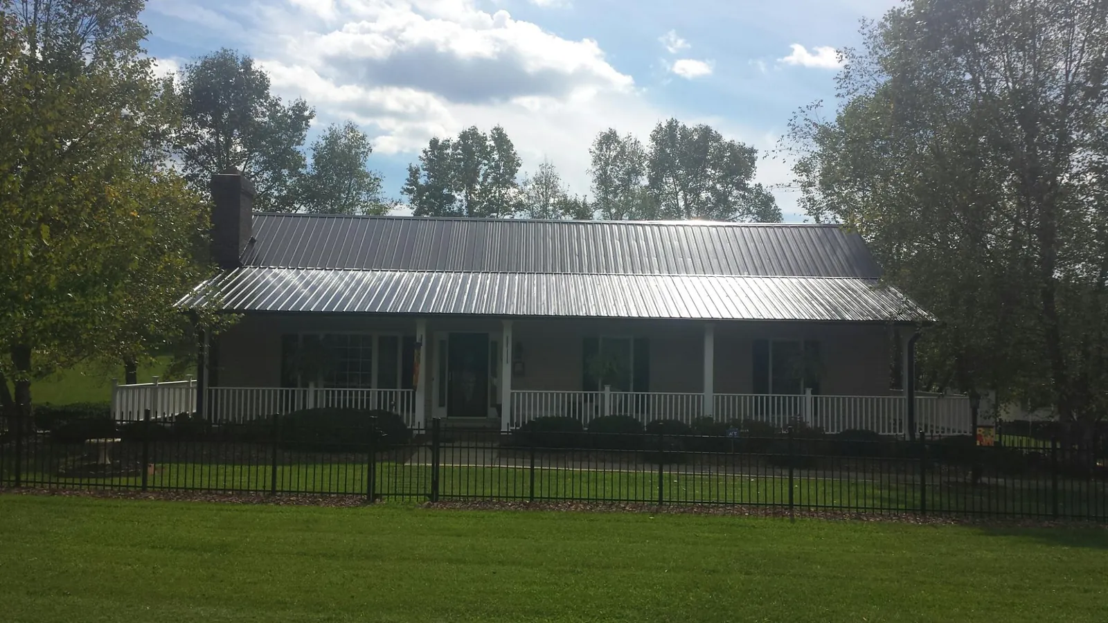 Gray metal roof on a brick ranch with a full width front porch — Gutter Guard Installation work by our crew in Mcmechen