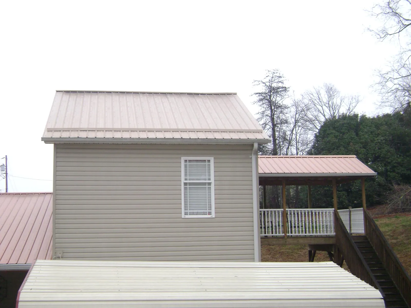 Tan metal roofs on a two story addition and attached porch, from a Roof Replacement job in Mcmechen