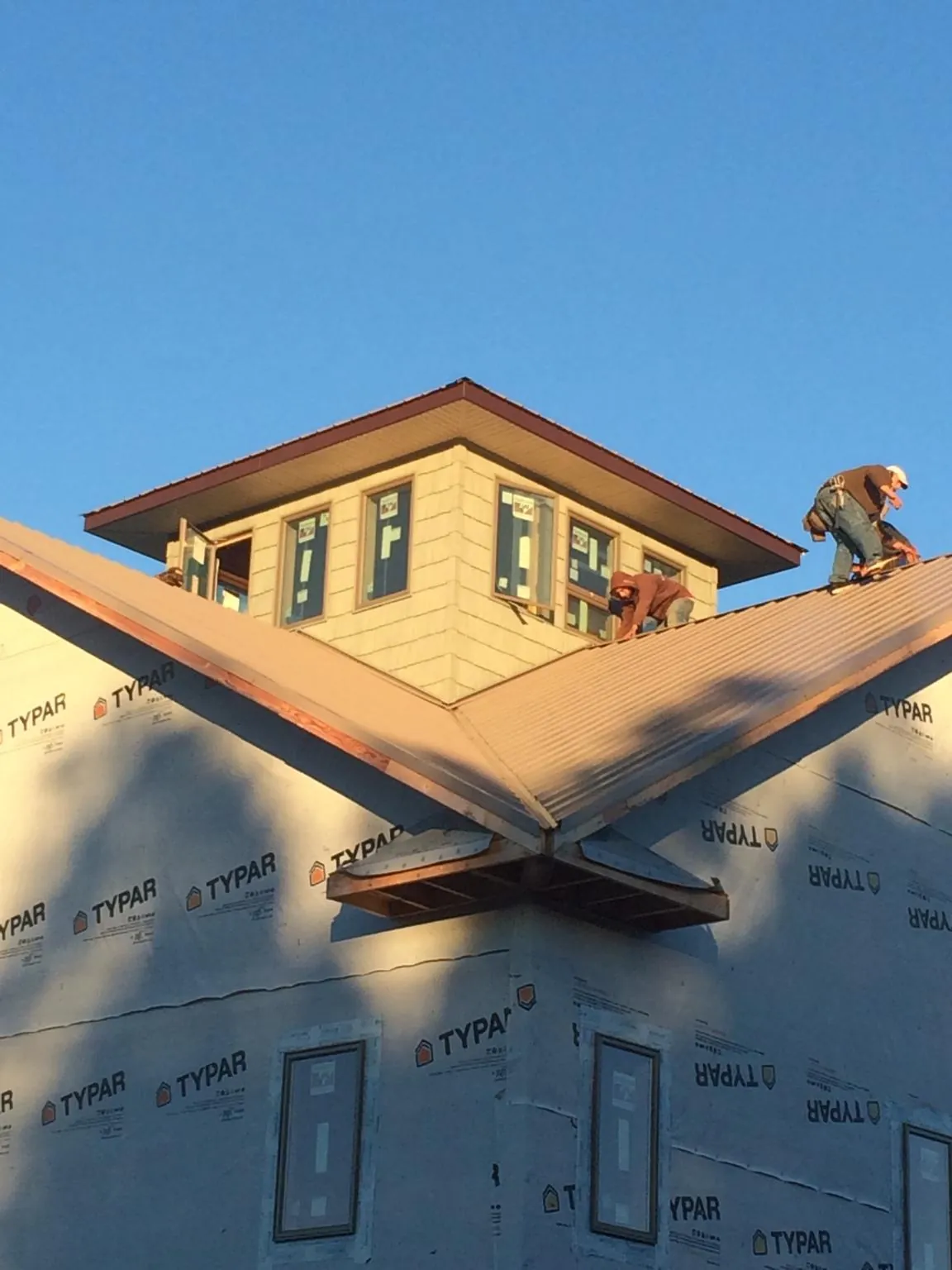 Roofers working around a rooftop cupola on a new metal roof at sunset — Roof Waterproofing in Mcmechen by Roofing Brothers